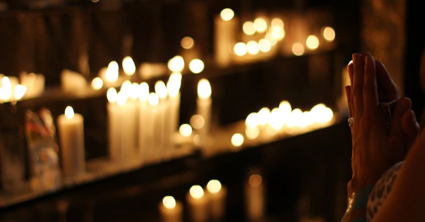 Religion - Close Up Photograph of Person Praying in Front Lined Candles