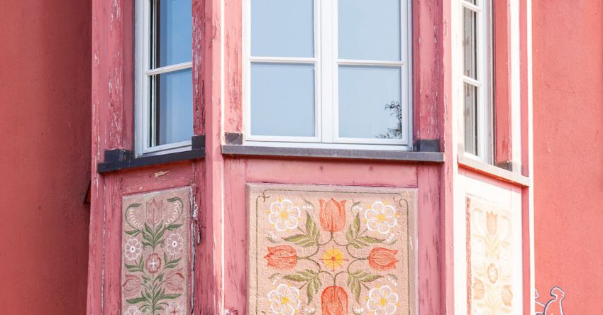 Dialect - Colorful hand painted pink or soft red Bay Window with sentence in german - this house is mine but it is not mine, life is short. Stein am Rhein in Switzerland